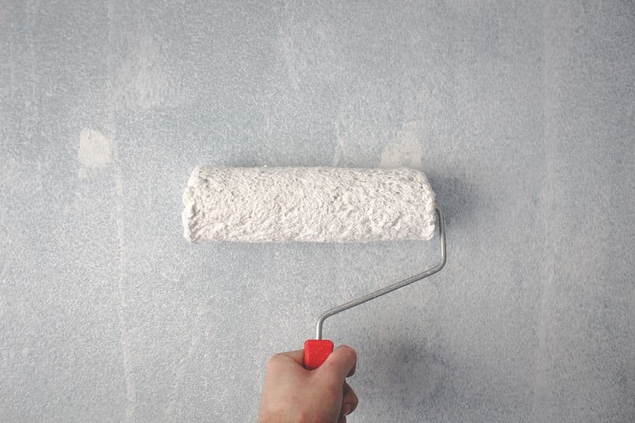 Detail van een geschilderde muur met roller
